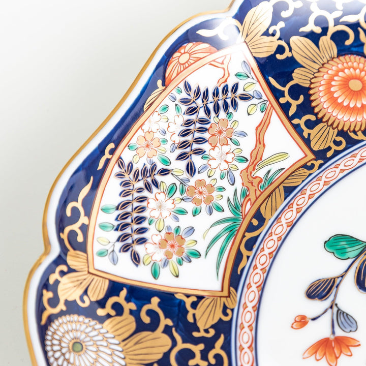 Japanese porcelain serving plate with chrysanthemum and peony motifs in vivid colors and gold detailing on a deep navy base