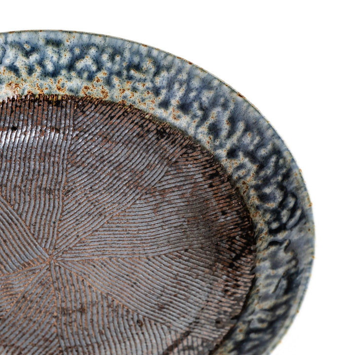 A pasta bowl with a textured glaze in blue, brown, and cream hues, featuring a ridged interior.