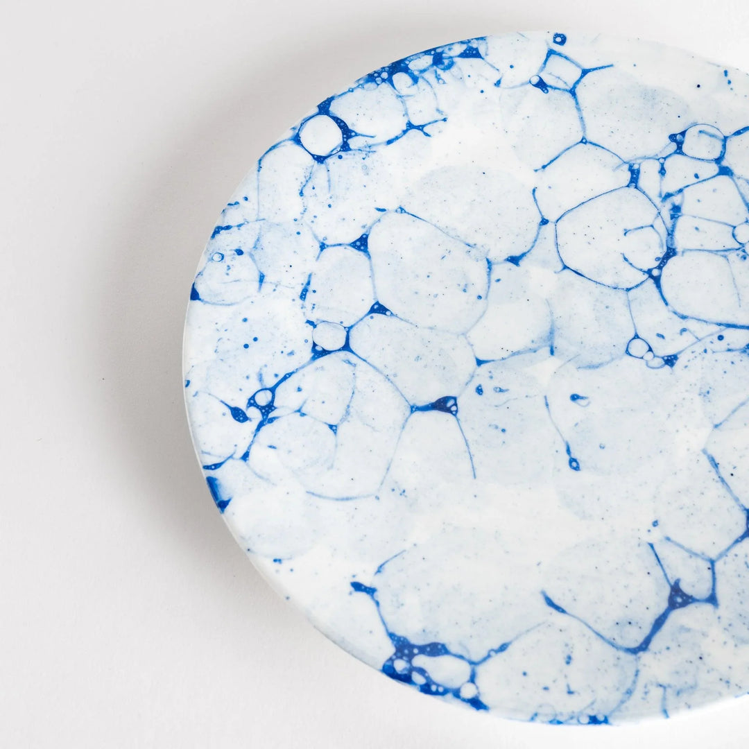 A round dinner plate with a blue bubble-like design on a white background.