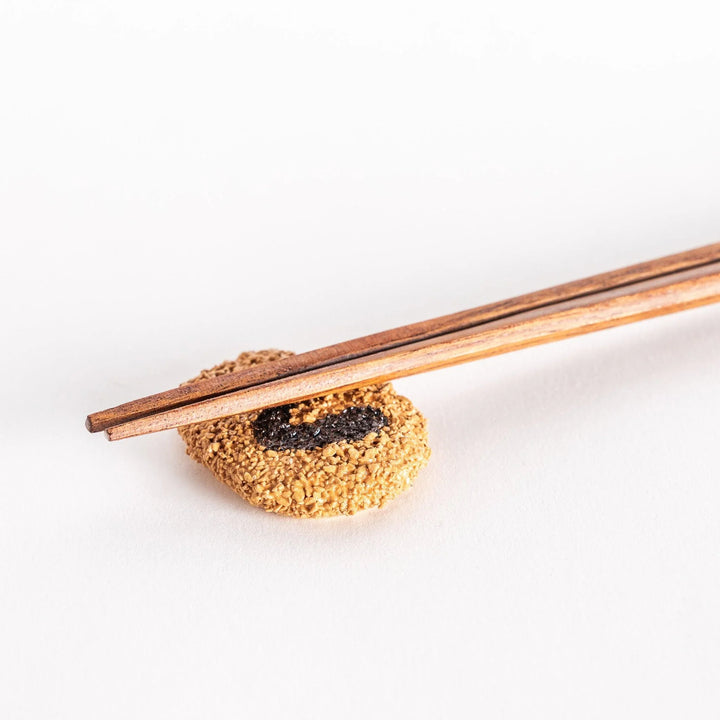 Japanese croquette shaped ceramic chopstick rest with golden brown finish adding fun dining accent.