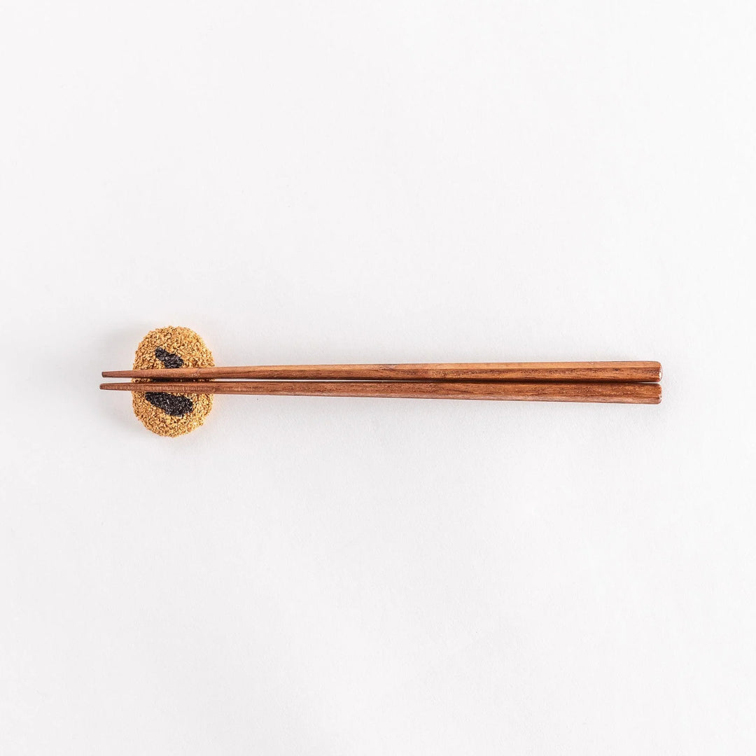 Japanese croquette shaped ceramic chopstick rest with golden brown finish adding fun dining accent.