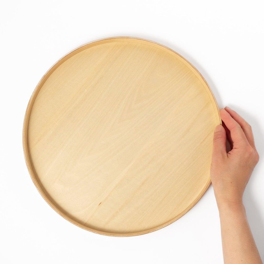 Minimalist Japanese round wooden tray with raised edge for serving tea snacks or organizing small items.