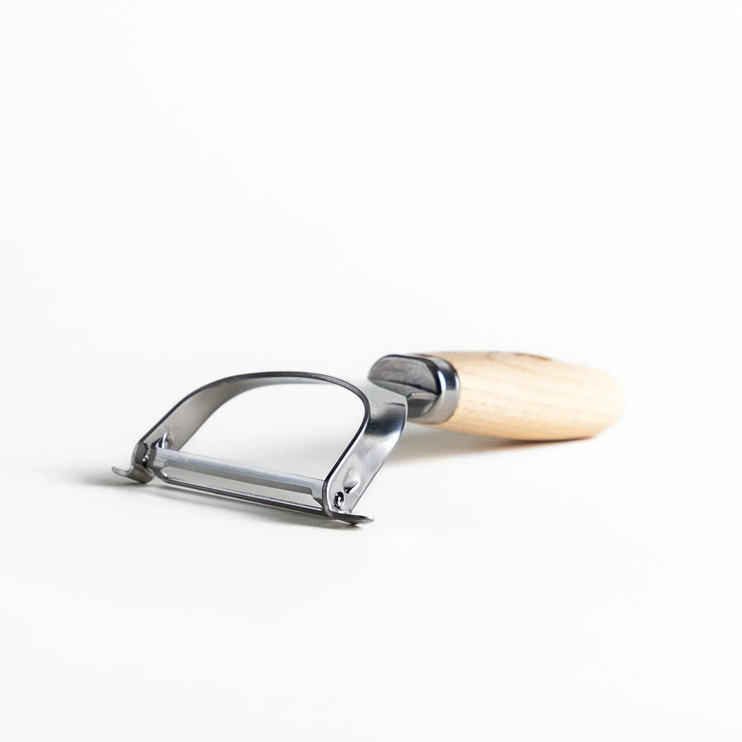 Japanese wood handle peeler with sharp stainless steel blade designed for smooth effortless vegetable peeling.