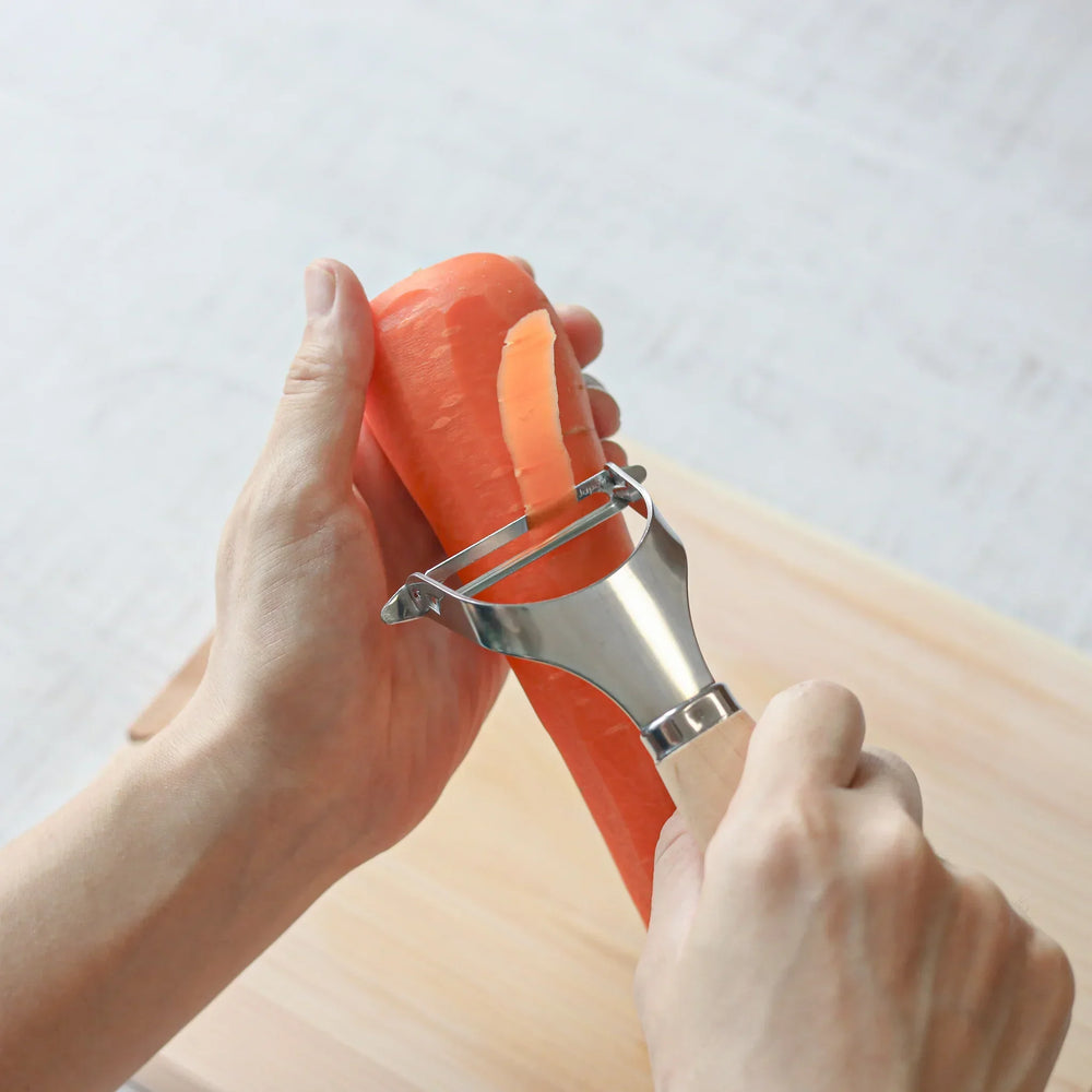 Japanese wood handle peeler with sharp stainless steel blade designed for smooth effortless vegetable peeling.