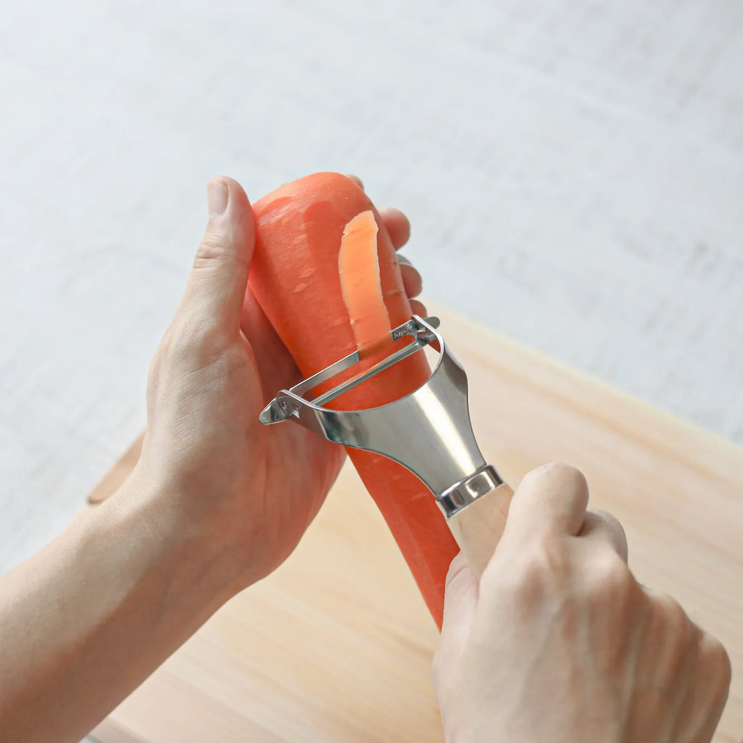 Japanese wood handle peeler with sharp stainless steel blade designed for smooth effortless vegetable peeling.