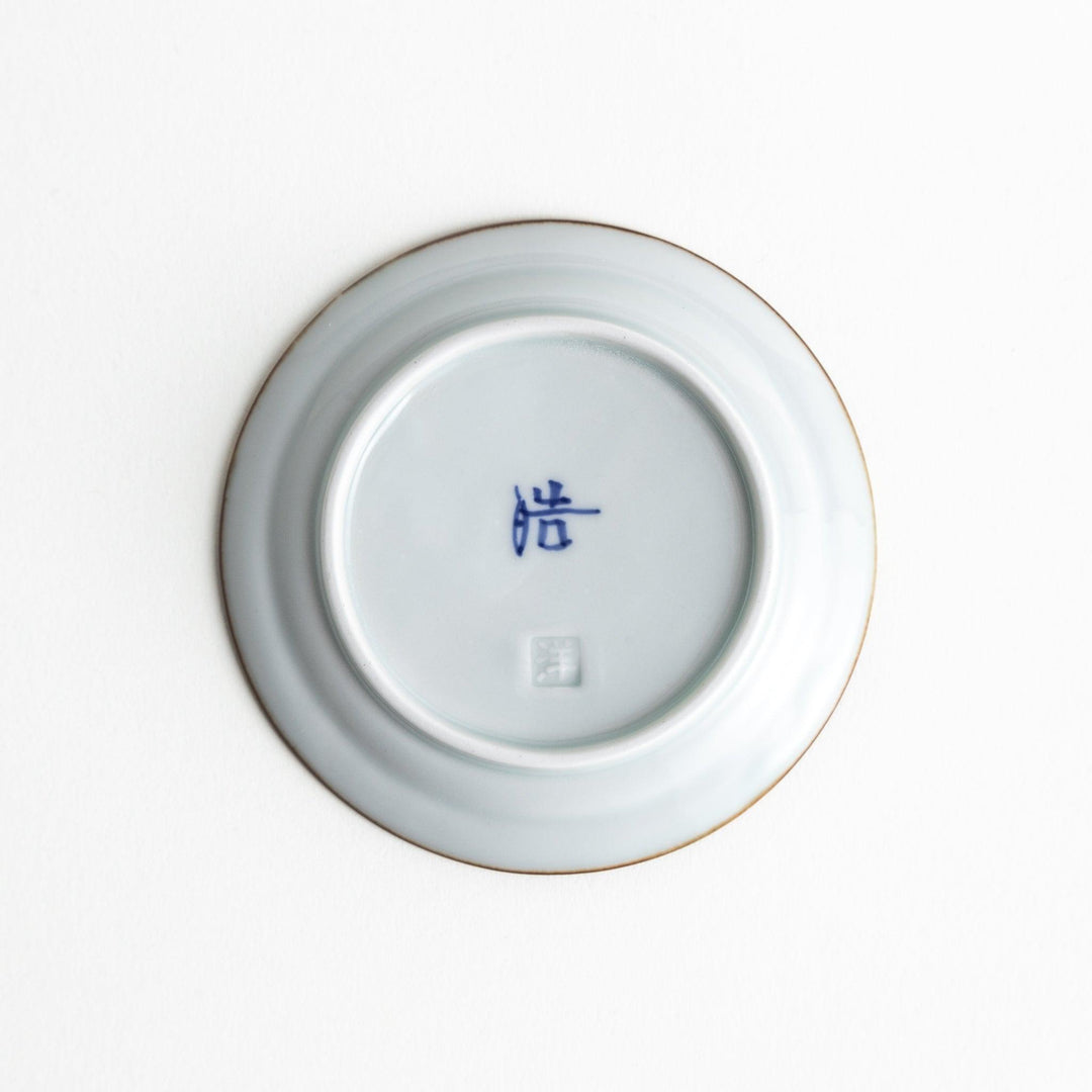 Small scalloped Japanese porcelain sauce dish with blue floral leaf pattern and brown accent trim.