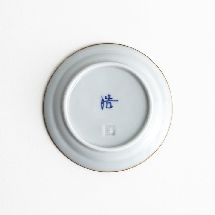 Small scalloped Japanese porcelain sauce dish with blue floral leaf pattern and brown accent trim.