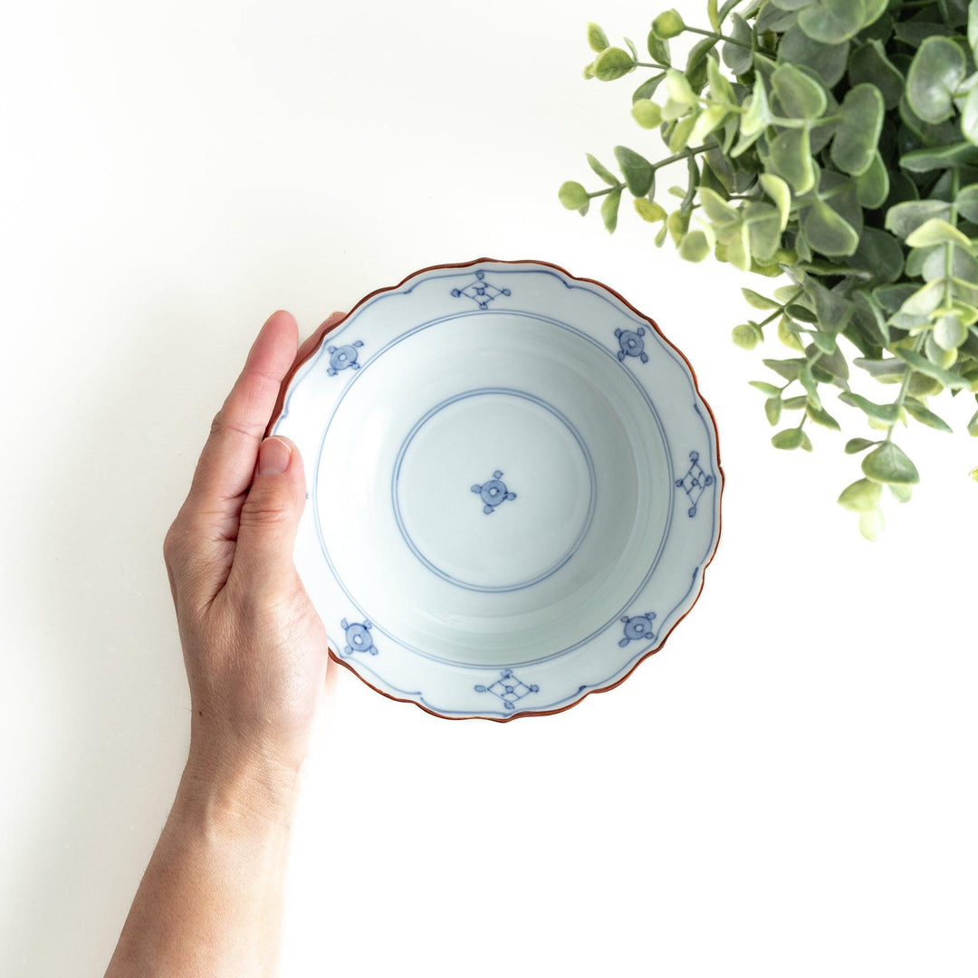 A ceramic bowl featuring a blue geometric motif and scalloped edges.