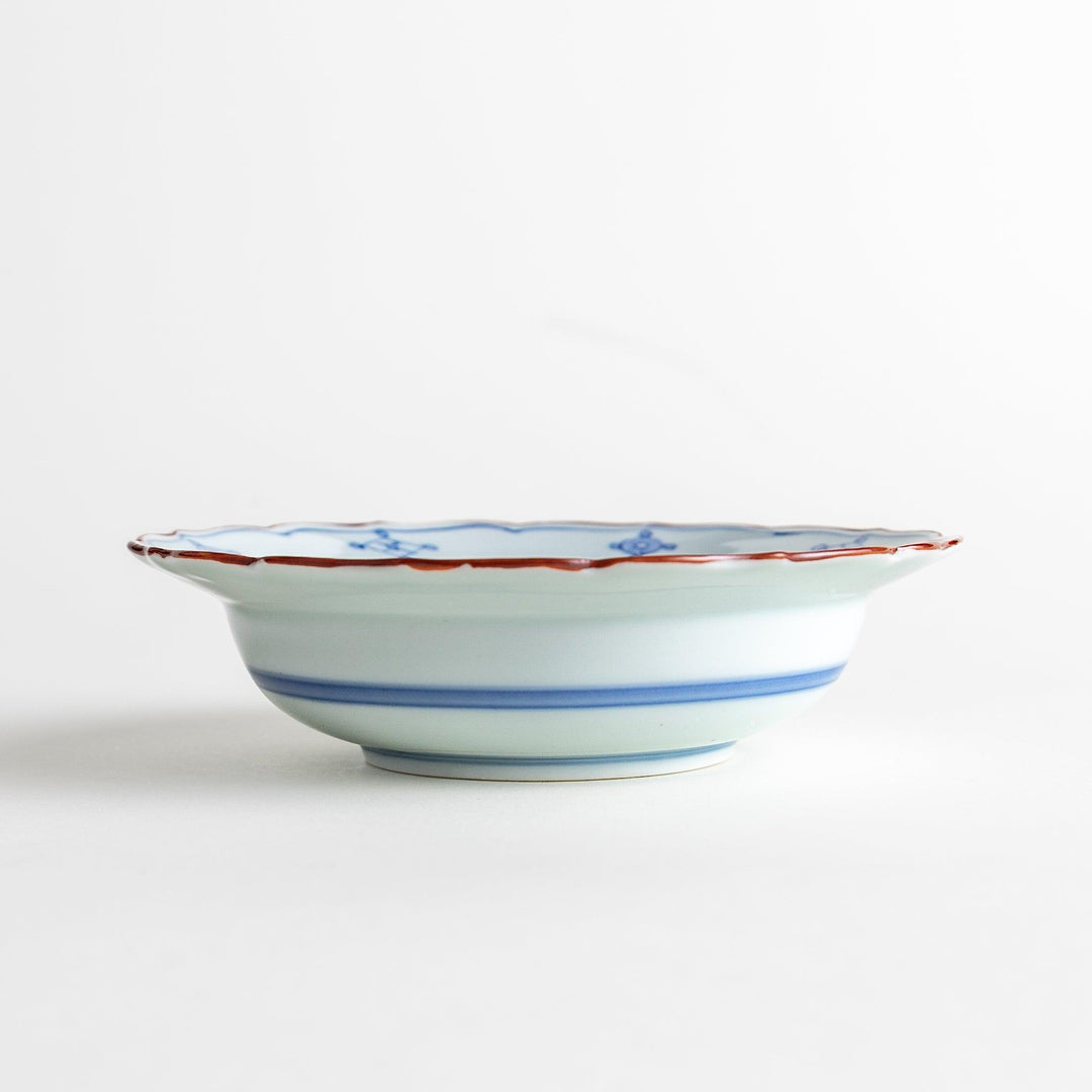 A ceramic bowl featuring a blue geometric motif and scalloped edges.