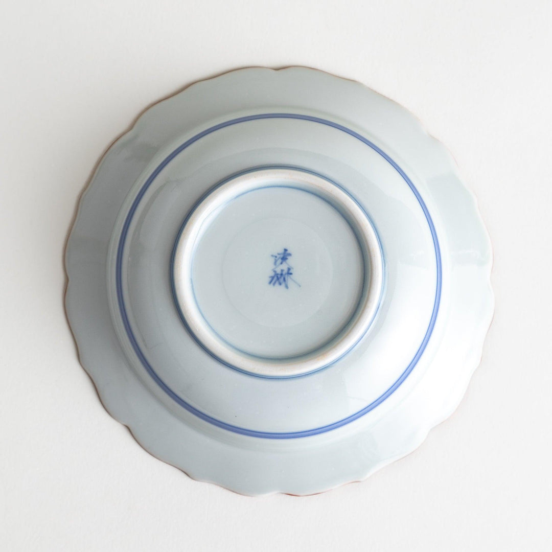 A ceramic bowl featuring a blue geometric motif and scalloped edges.