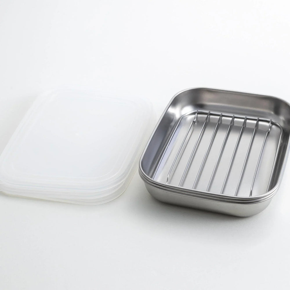 Rectangular stainless steel food prep trays with a wire rack and a white plastic lid.
