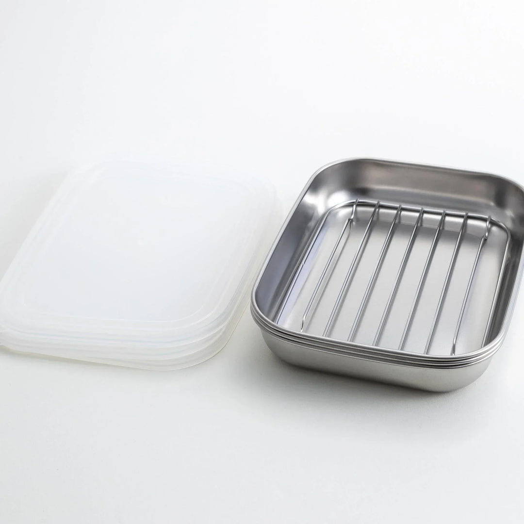 Rectangular stainless steel food prep trays with a wire rack and a white plastic lid.