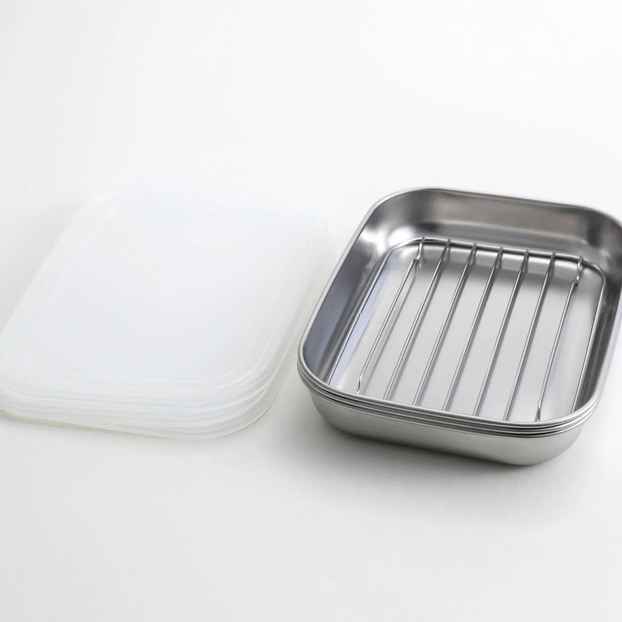 Rectangular stainless steel food prep trays with a wire rack and a white plastic lid.