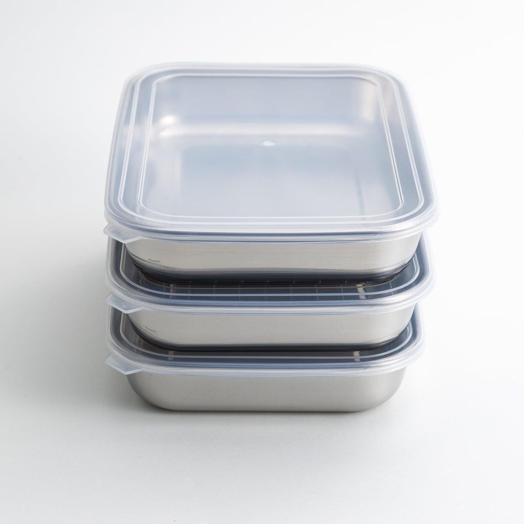 Rectangular stainless steel food prep trays with a wire rack and a white plastic lid.