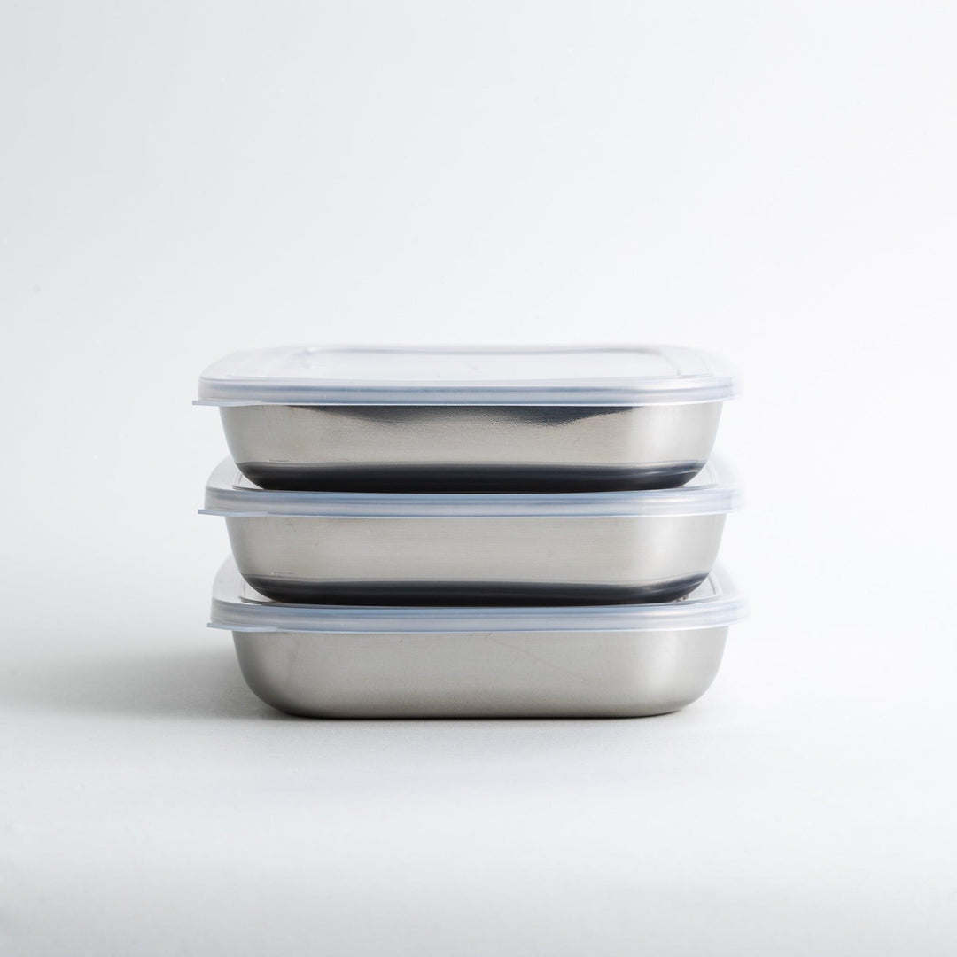 Rectangular stainless steel food prep trays with a wire rack and a white plastic lid.