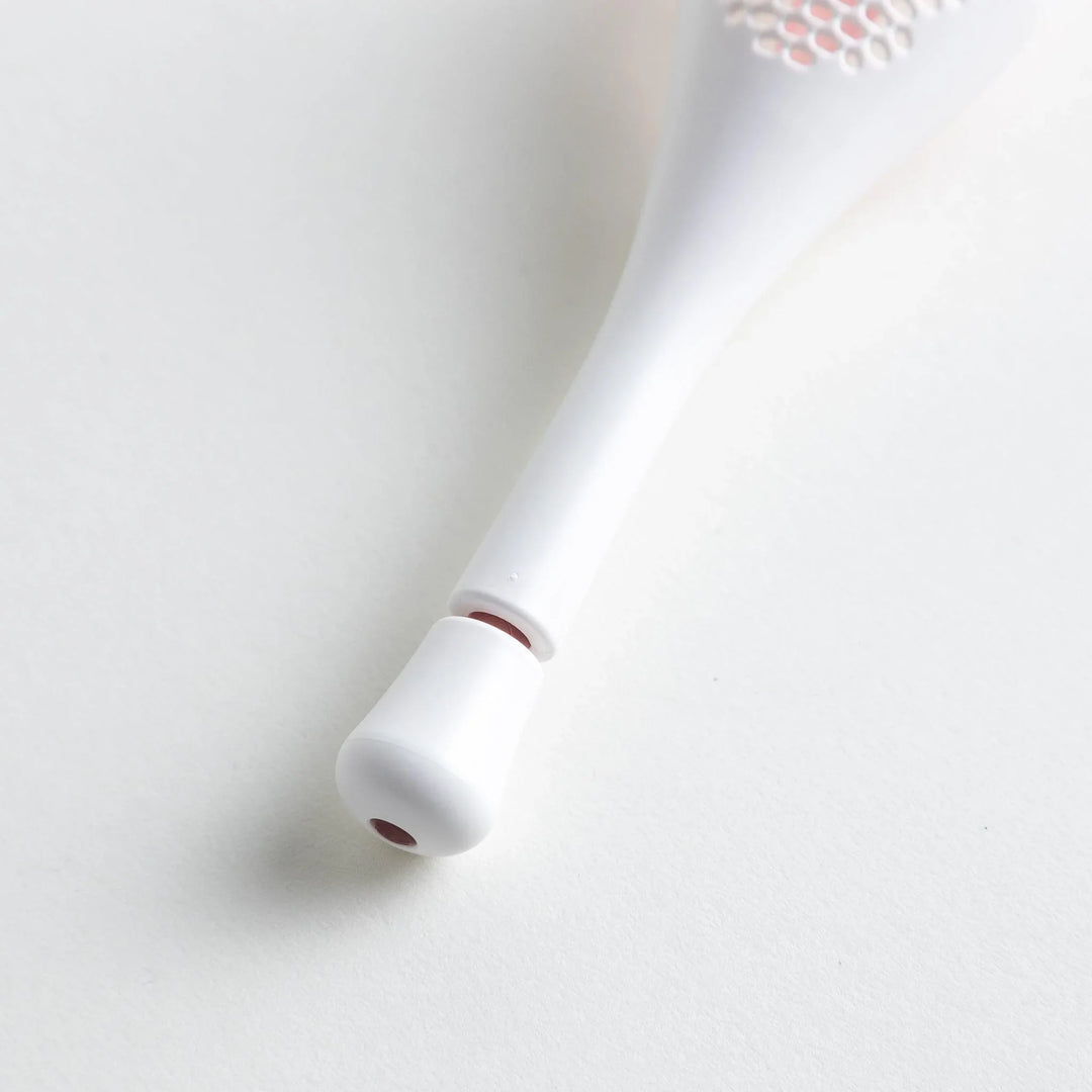 – A modern, white maraca-shaped spice sifter with a textured surface and a pink handle.