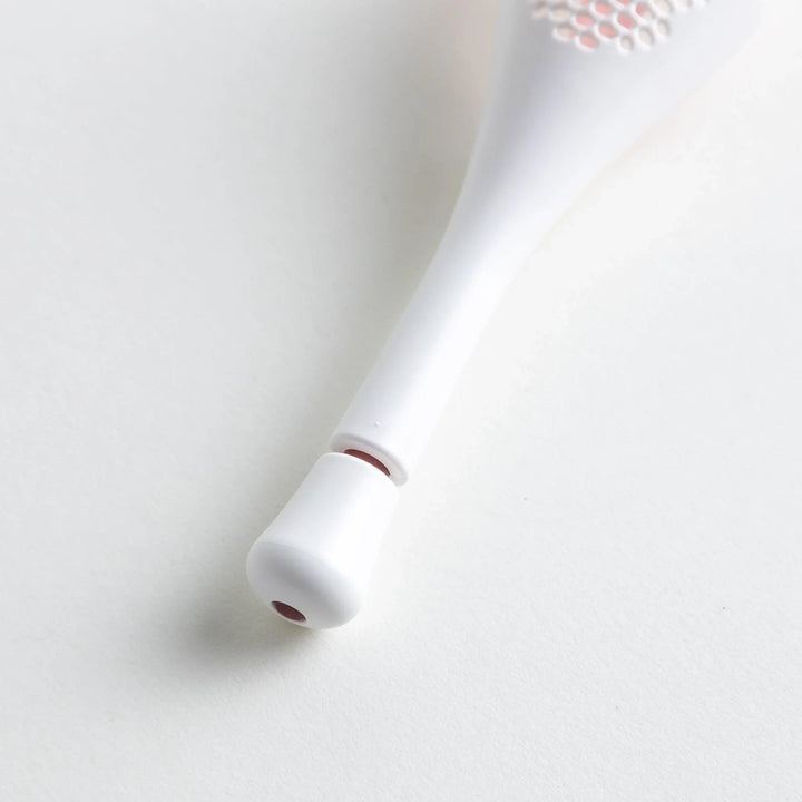 – A modern, white maraca-shaped spice sifter with a textured surface and a pink handle.