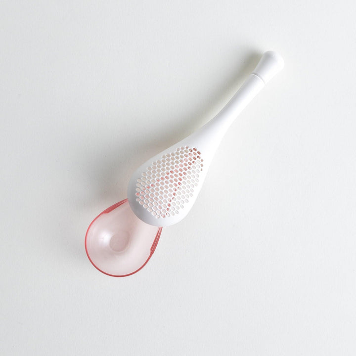 – A modern, white maraca-shaped spice sifter with a textured surface and a pink handle.
