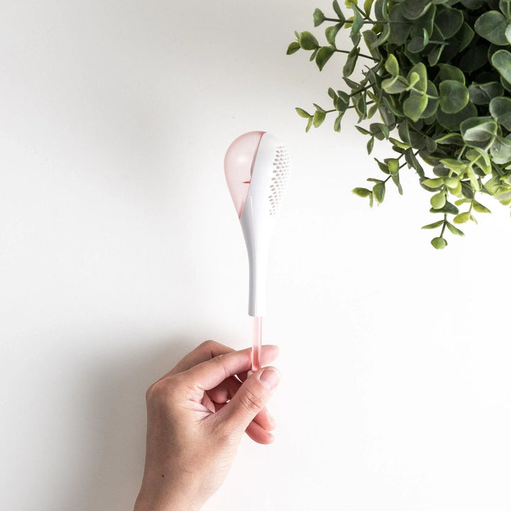 – A modern, white maraca-shaped spice sifter with a textured surface and a pink handle.
