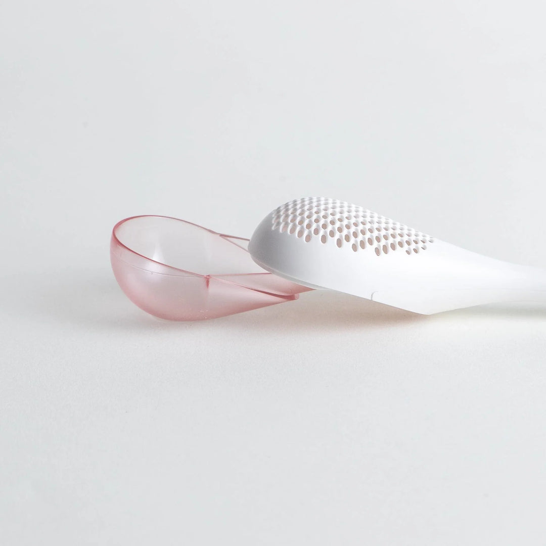 – A modern, white maraca-shaped spice sifter with a textured surface and a pink handle.