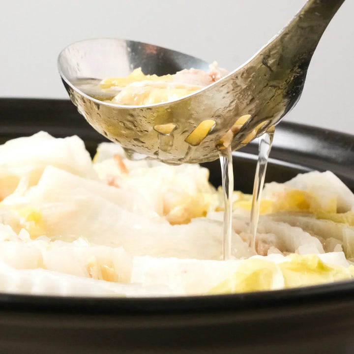 Scooping hot pot with the AUX Japanese Large Draining Ladle, ideal for serving broth while draining excess liquid with ease.