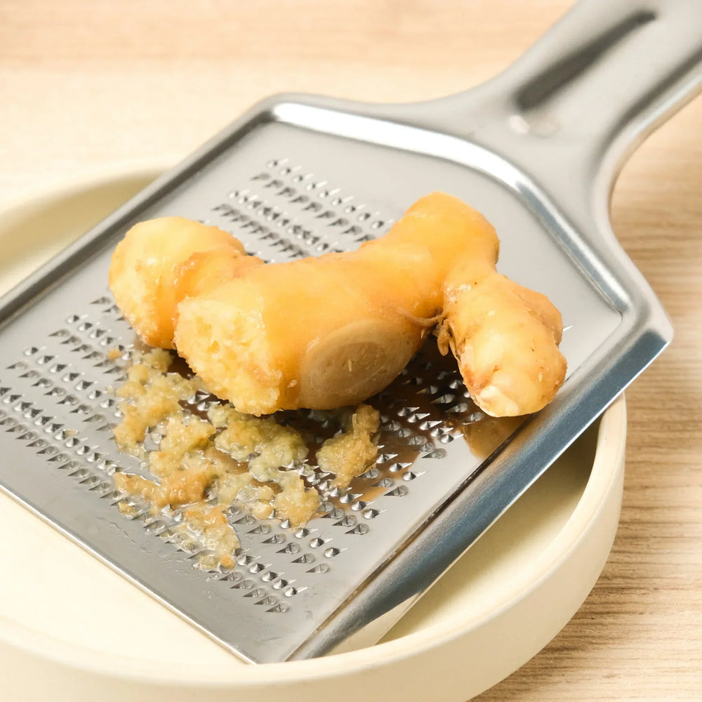 Stainless steel grater with sharp blades and ergonomic handle ideal for cheese vegetables and spices.