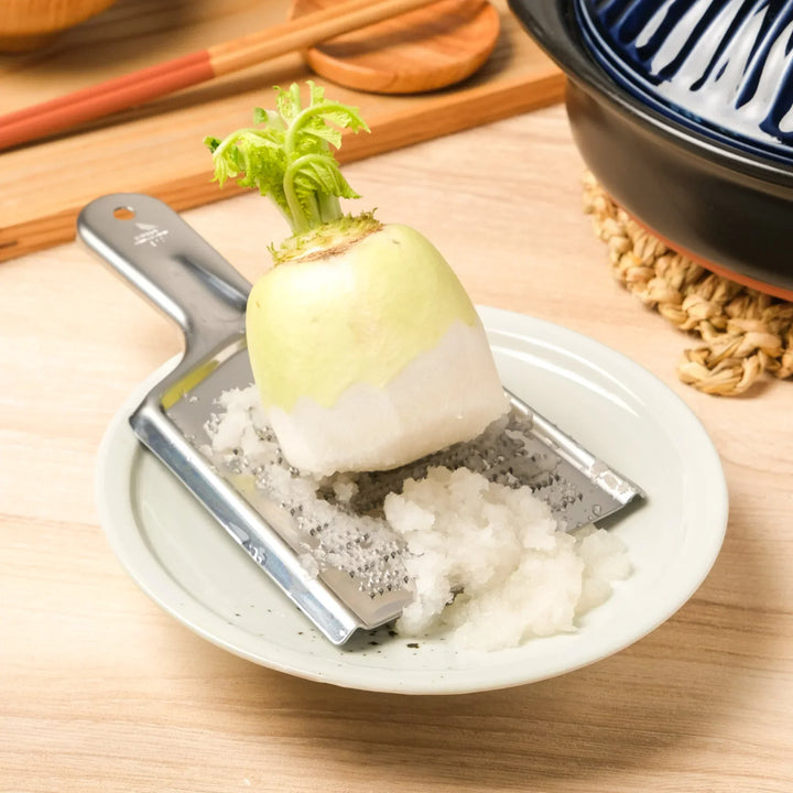 Grating daikon radish on a Premium Stainless Steel Large Double-Sided Grater, perfect for fast prep and fine, fluffy texture.