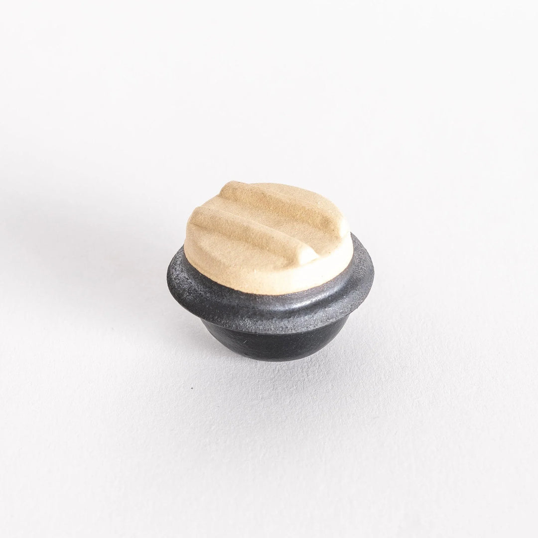 Kamameshi chopsticks rest photographed at a slight angle, showcasing its lid and pot shape.