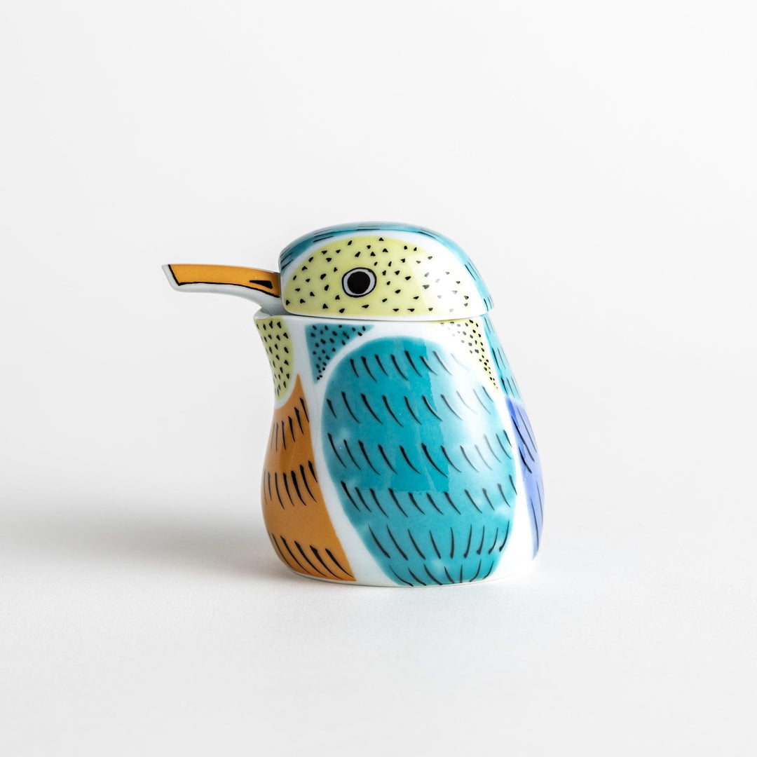 A bird-shaped ceramic soy sauce dispenser with vibrant patterns in turquoise, yellow, and green.