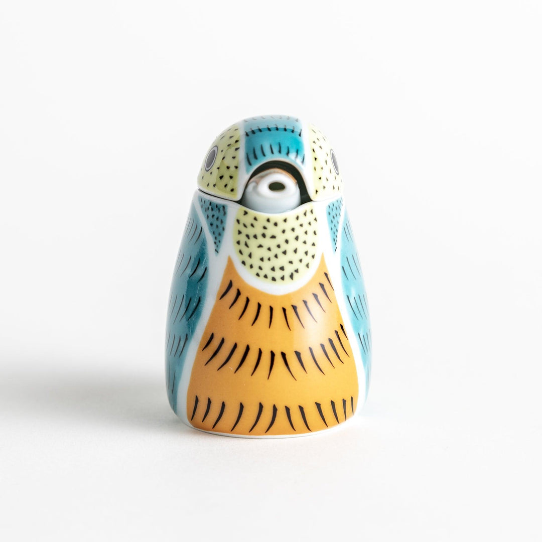 A bird-shaped ceramic soy sauce dispenser with vibrant patterns in turquoise, yellow, and green.