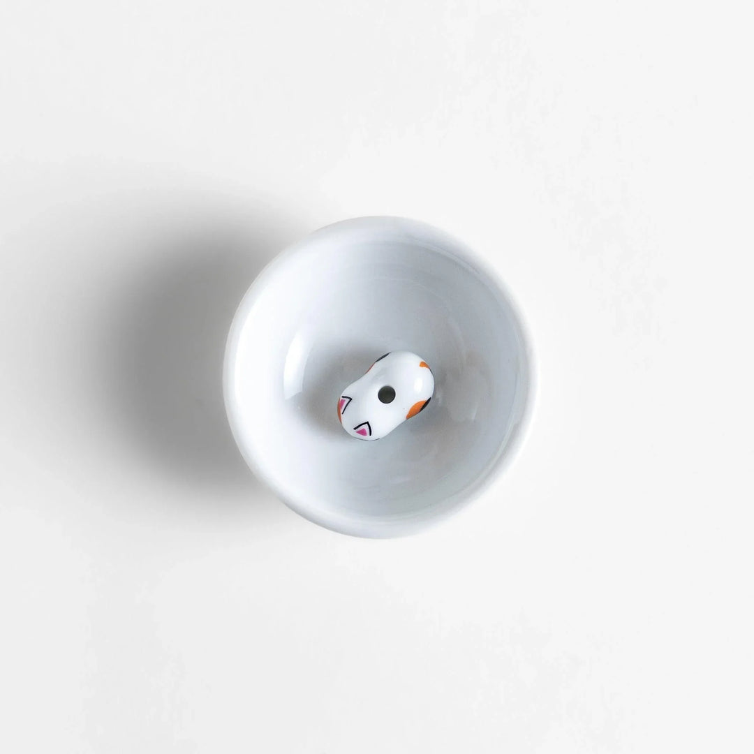 White ceramic incense holder with a small calico cat figurine inside the bowl, adding a touch of warmth to your daily rituals