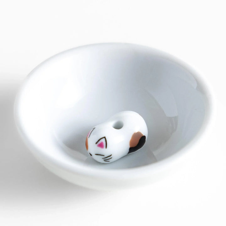 White ceramic incense holder with a small calico cat figurine inside the bowl, adding a touch of warmth to your daily rituals