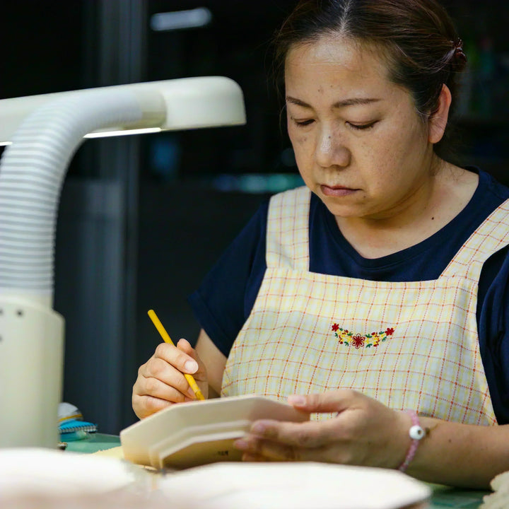 Artisan preparing to paint a ceramic plate by marking guide lines during the hand decorating process