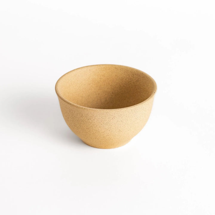 Slightly angled shot of a beige ceramic teacup, emphasizing its balanced form and artisanal craftsmanship.