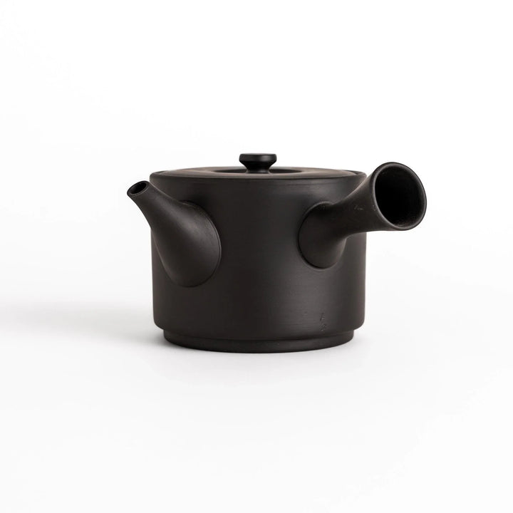 Modern black teapot with round body and horizontal spout crafted from textured ceramic for tea.