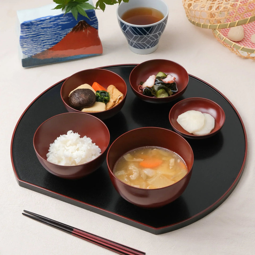 Japanese Oryoki bowl set with rice miso soup vegetables pickles and octopus salad on lacquer tray with tea.