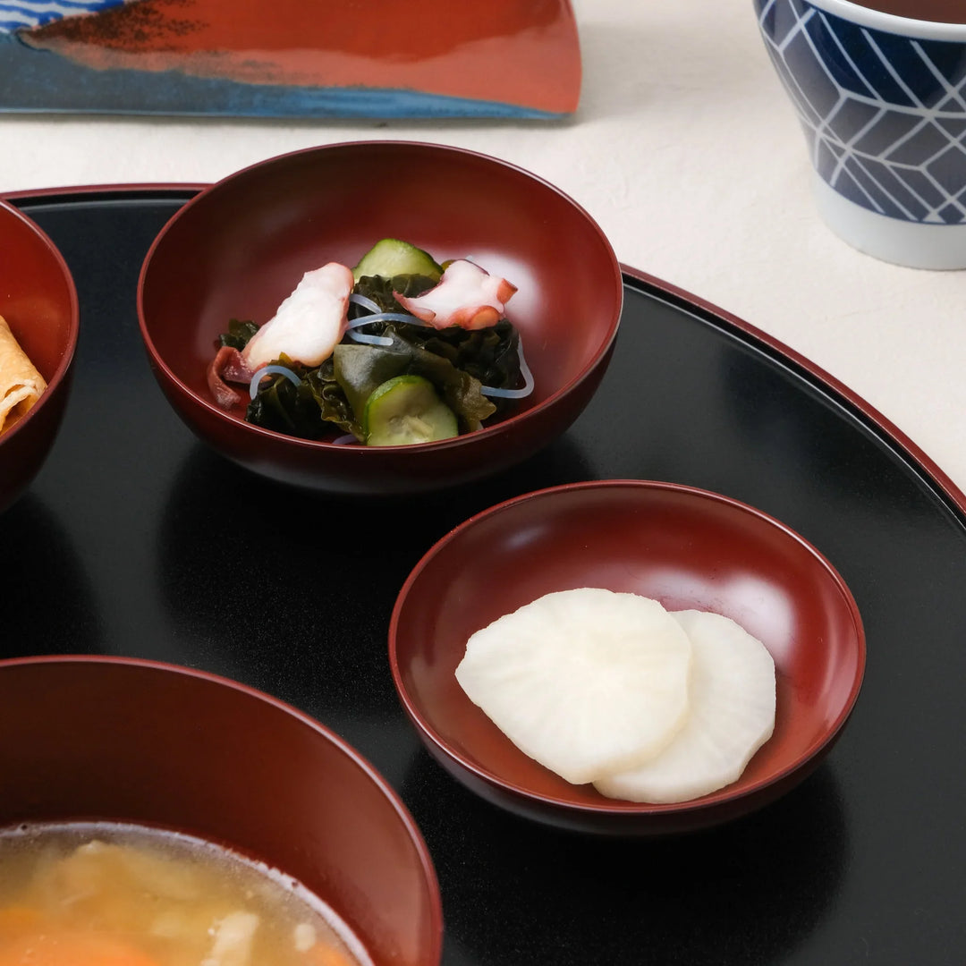 Japanese Oryoki bowl set with rice miso soup vegetables pickles and octopus salad on lacquer tray with tea.