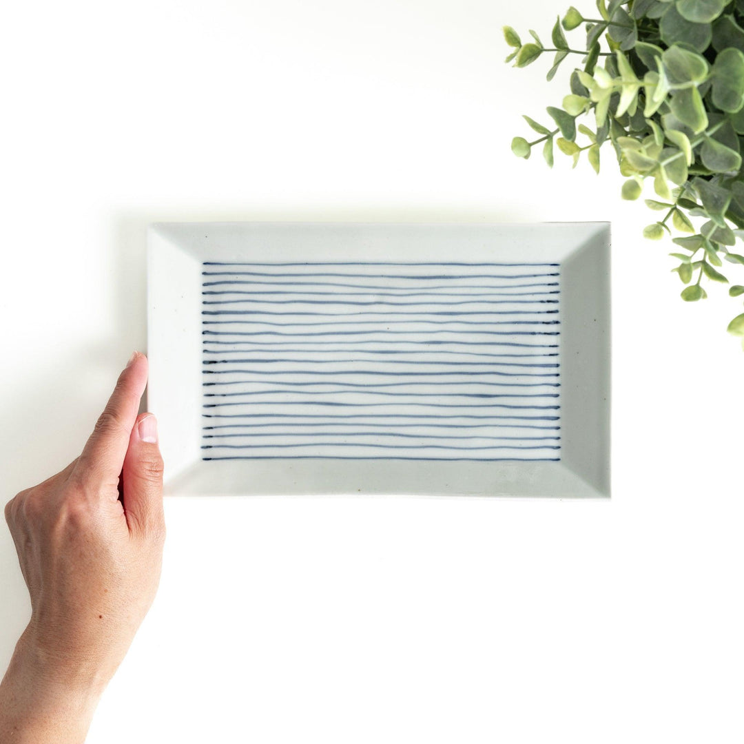 A rectangular ceramic plate with blue horizontal stripes, simple and elegant design.