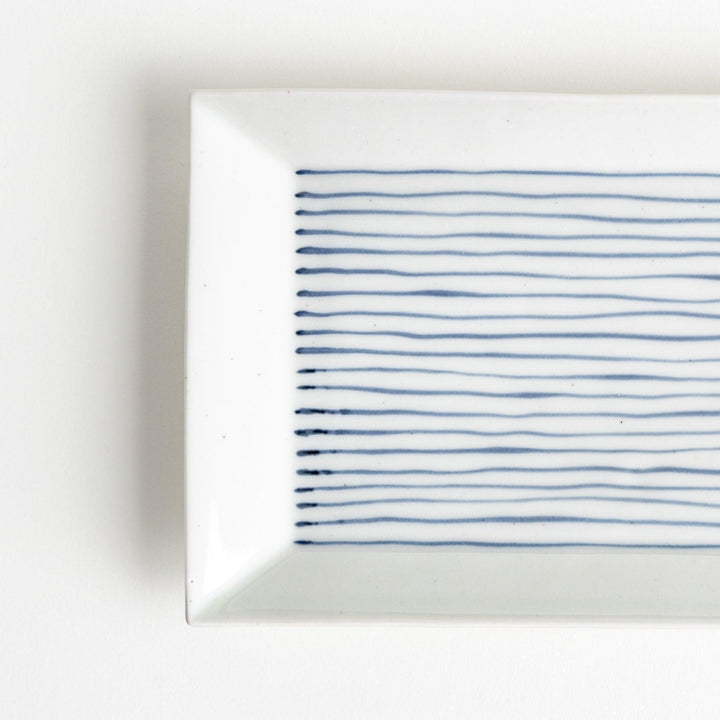 A rectangular ceramic plate with blue horizontal stripes, simple and elegant design.