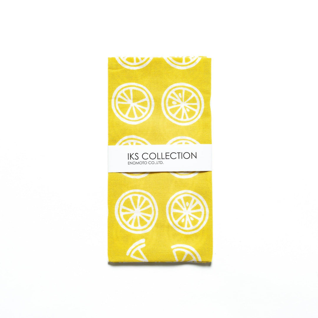 Yellow hand towel with white lemon slice motifs, folded with a branded sleeve.