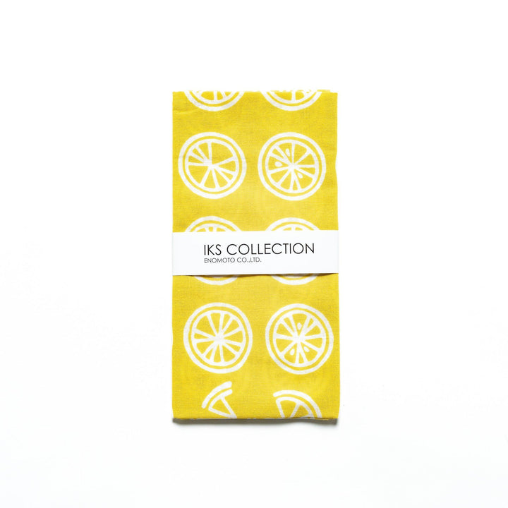 Yellow hand towel with white lemon slice motifs, folded with a branded sleeve.