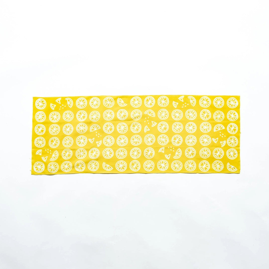 Yellow hand towel featuring white lemon slices, fully spread to showcase its design.