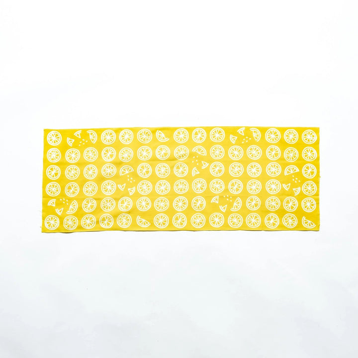 Yellow hand towel featuring white lemon slices, fully spread to showcase its design.