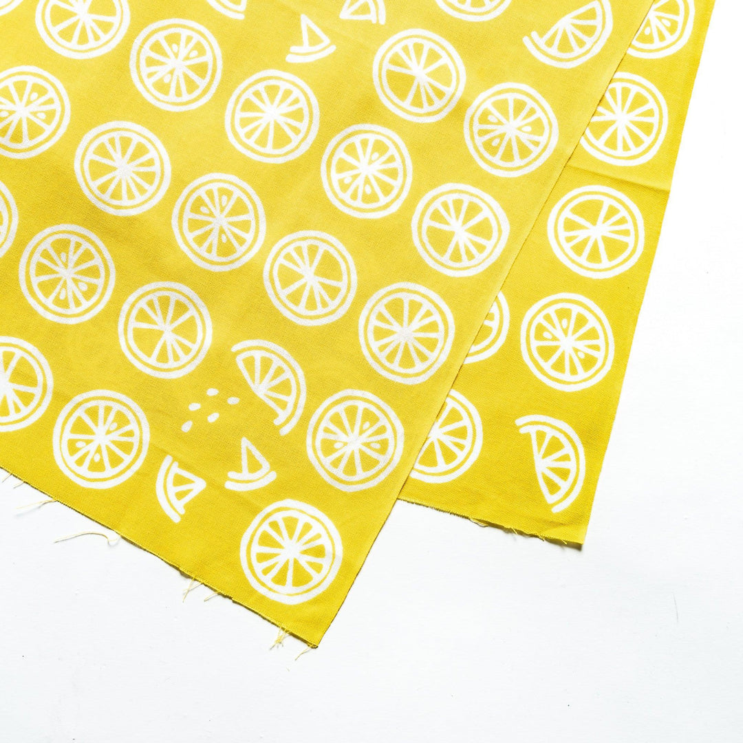 Close-up of white lemon slice patterns on bright yellow hand towel fabric.