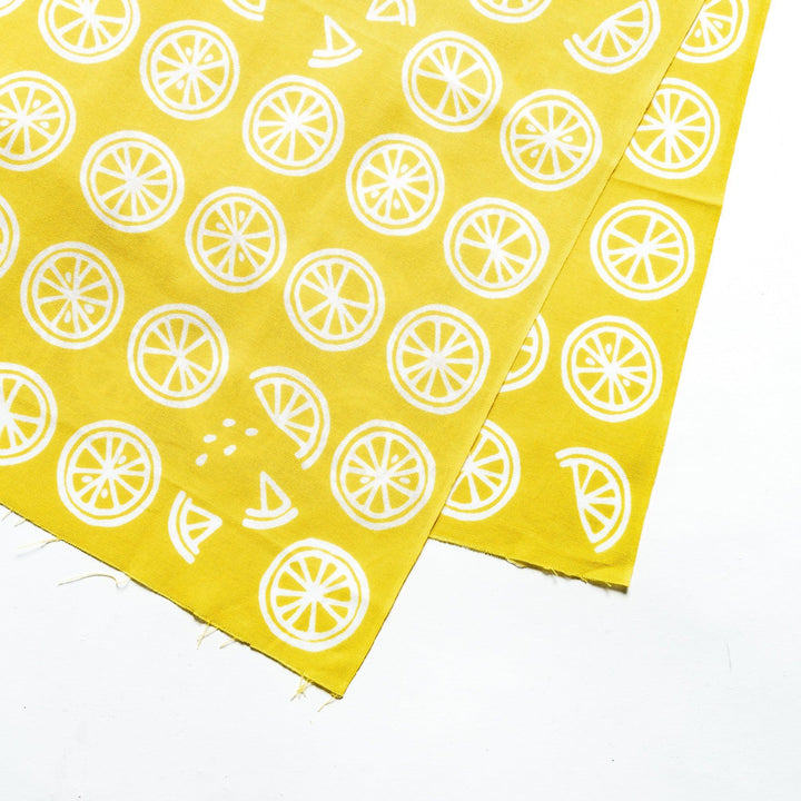 Close-up of white lemon slice patterns on bright yellow hand towel fabric.