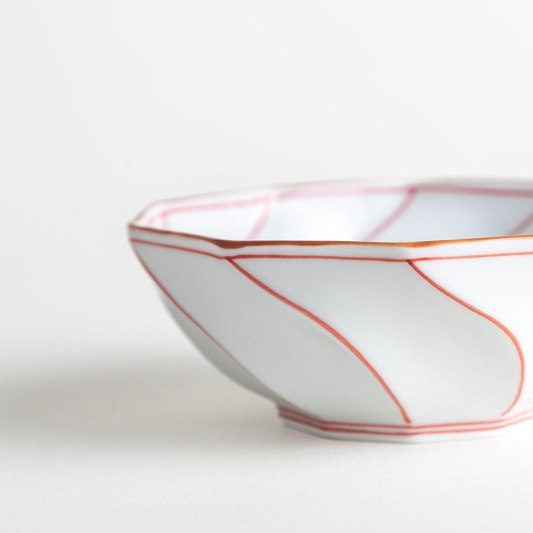 Deep white octagonal dessert bowl with a petal design, outlined in blue or red and finished with a brown rim.