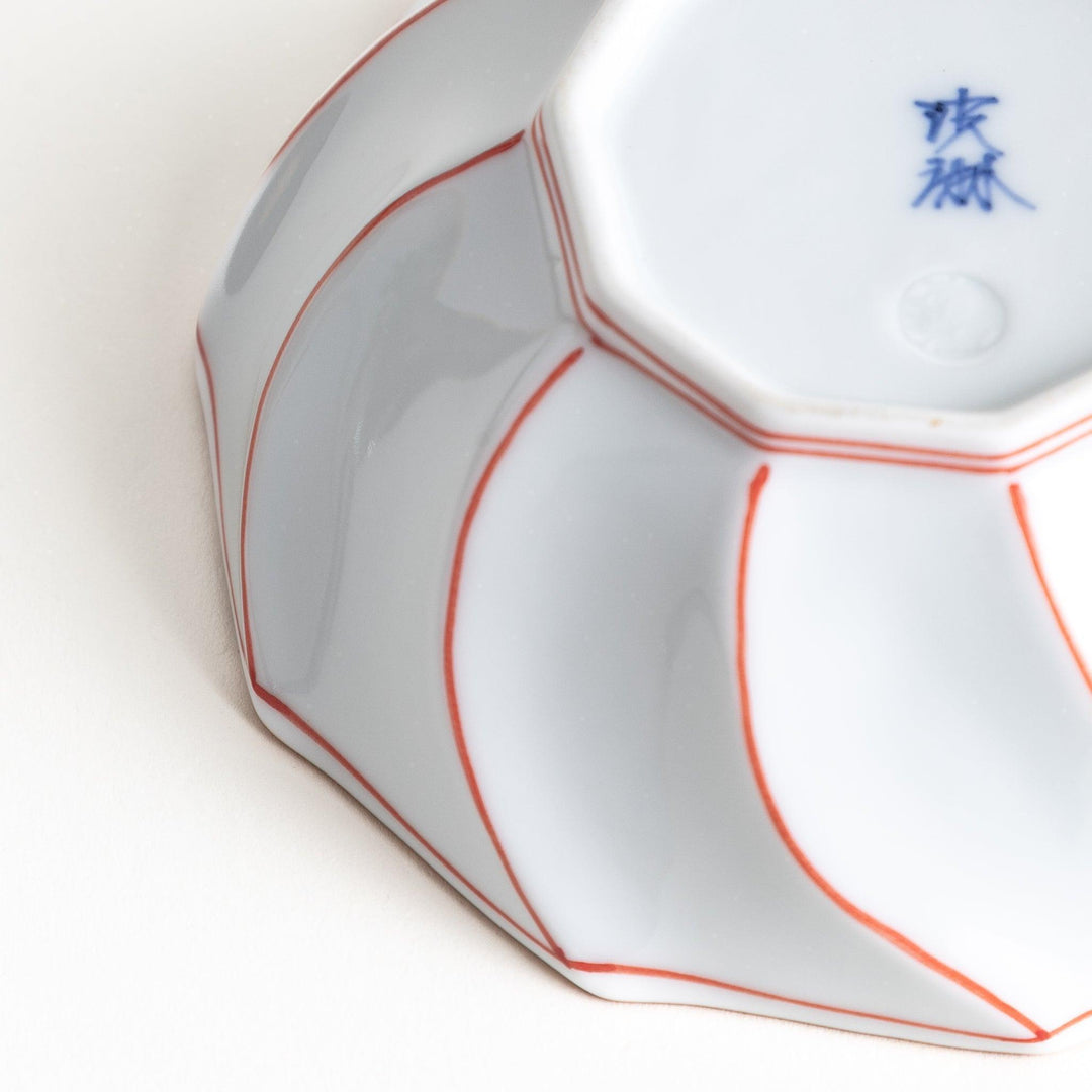 Deep white octagonal dessert bowl with a petal design, outlined in blue or red and finished with a brown rim.