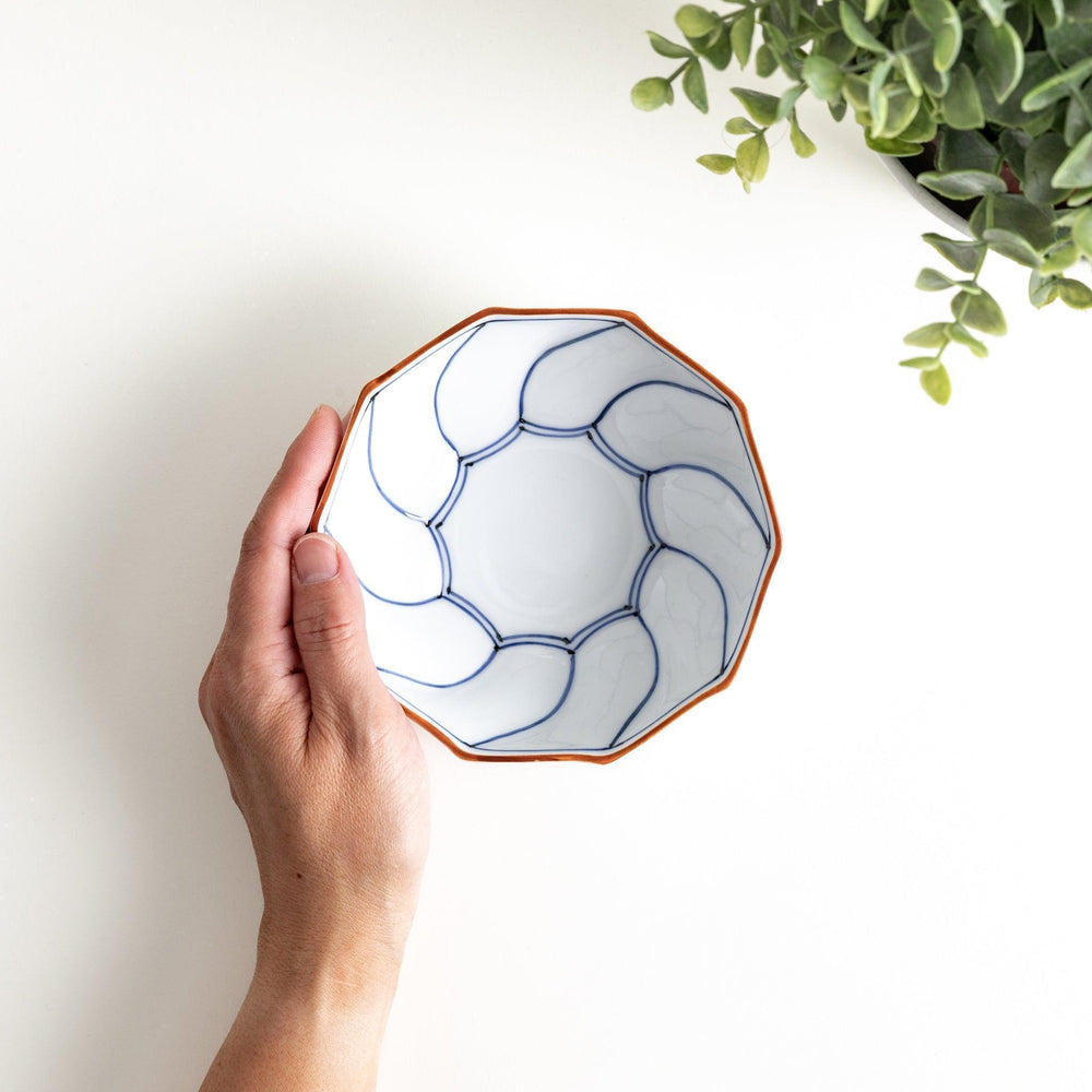 Deep white octagonal dessert bowl with a petal design, outlined in blue or red and finished with a brown rim.