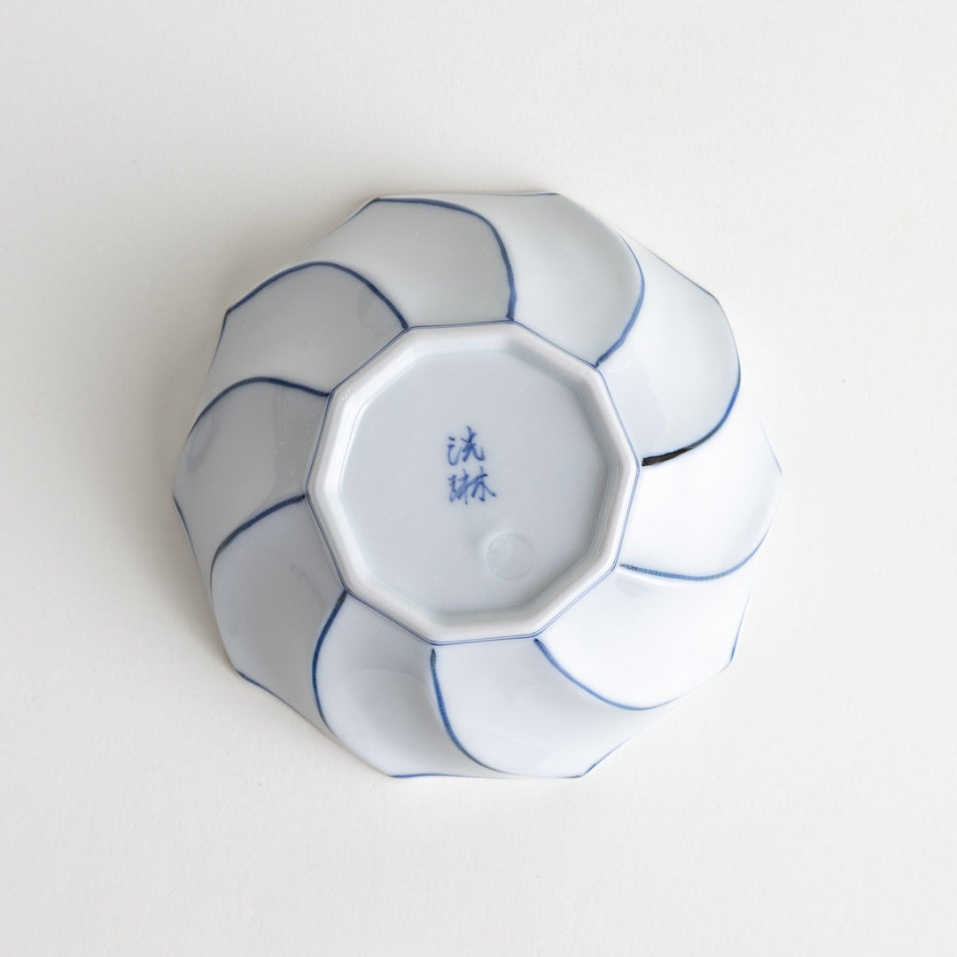 Deep white octagonal dessert bowl with a petal design, outlined in blue or red and finished with a brown rim.