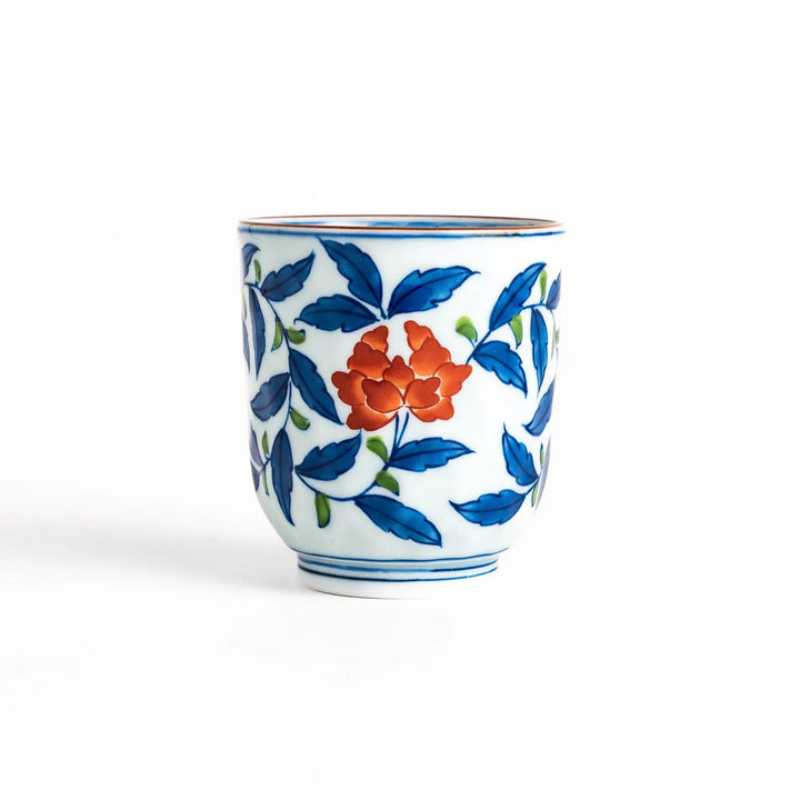 Porcelain teacup with vivid blue and orange floral design and green leaves showing fine Japanese artistry.
